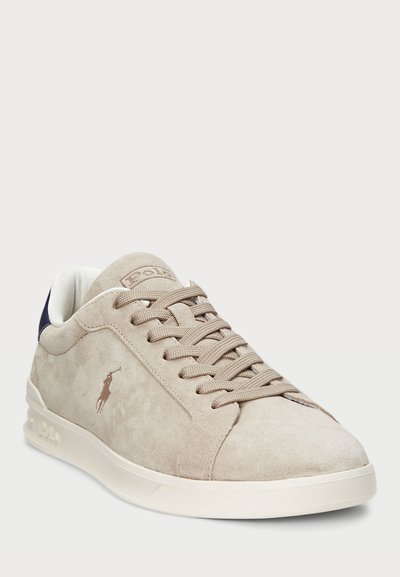 Bež usnjeni športni čevljih s ravnim zapiranjem na vezalke, teksturiran zgornji del, bela gumijasta podplat in mornarsko modri poudarek na peti. Majhen logotip na strani.