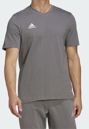 Šedé tričko s krátkým rukávem a výstřihem do V vyrobené z měkké látky, s vyšitým bílým logem Adidas na hrudi a volným střihem.