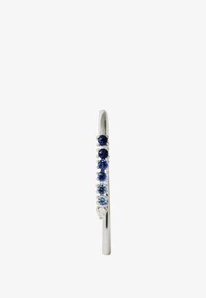 Anillo de plata con una fila vertical de gemas alternando entre azul oscuro y azul claro, dispuestas en tamaños graduados, con una banda lisa.