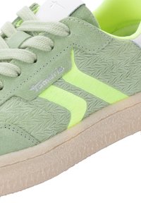 Hellgrüner Wildledersneaker mit einem strukturierten Design, Neongelben Akzenten, flachen Schnürsenkeln und einer strukturierten hellfarbenen Sohle.