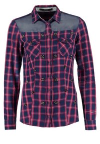 Chemise à manches longues à carreaux bleu marine et rouge avec empiècement supérieur transparent, fermeture boutonnée, poches poitrine et petites décorations florales à l'avant.