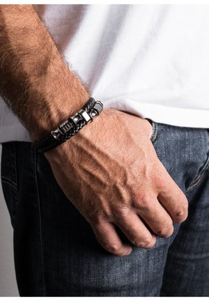 Black braided leather bracelet with silver metal accents, featuring textured patterns and a mix of smooth and ridged surfaces.