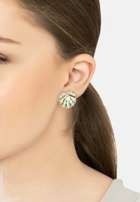 Pendientes dorados con un diseño floral, acentos verdes, una perla central y piedras brillantes, elementos texturizados en forma de pétalos.
