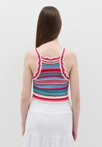 Top corto lavorato a maglia con motivi a righe colorate in rosso, blu e verde, caratterizzato da spalline ondulate e un bordo aderente alla base.