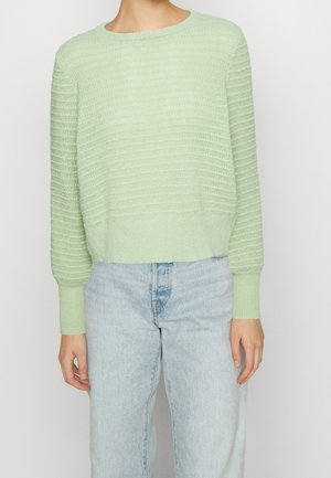 Helles grünes Strickpullover mit strukturiertem Streifenmuster, rundem Ausschnitt und gerippten Bündchen sowie Saum, kombiniert mit hellblauen Jeans.