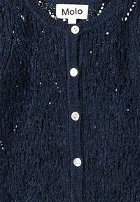 Marinblå stickad cardigan med en strukturerad mönster, med rund halsringning och fem vita knappar. Etiketten säger "Molo."