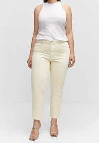 Jeans color crema, a gamba affusolata con leggero elasticizzato, dotati di chiusura a bottone e cerniera, tasche anteriori e cuciture a contrasto sottili.
