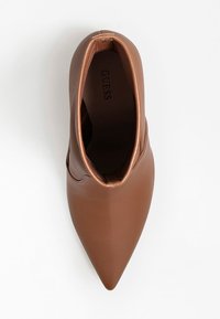 Botte chelsea en cuir marron à bout pointu avec un design à enfiler et le logo GUESS visible à l'intérieur de la chaussure.