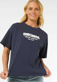 Camiseta de algodón azul marino de mangas cortas, con un gráfico de texto blanco que dice "Rip Curl Surfing Company" y "Desde 1969" impreso en el frontal.