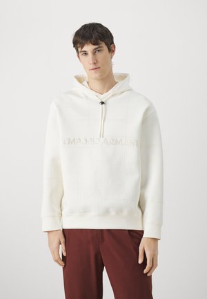 Sudadera blanca con capucha, con costuras texturizadas, que presenta el nombre de la marca "EMPORIO ARMANI" en relieve en el pecho y una capucha con cordones.