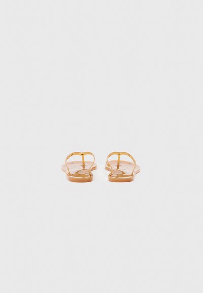 Șlapi maro din cauciuc cu bretele subțiri. Tălpi plate și model circular pe talpă. Design minimalist cu stil cu vârf deschis.