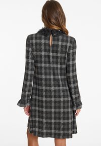Gray and black plaid dress with long sleeves, a ruffled collar, and a keyhole back detail. Made of a soft textured fabric.