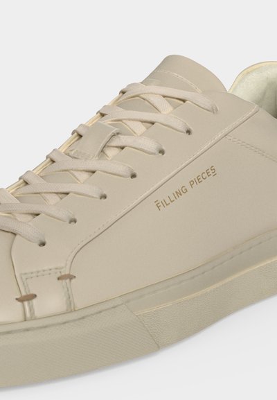 Μπεζ παπούτσι τύπου sneaker με χαμηλή κορυφή, ταιριαστά κορδόνια και σήμανση "Filling Pieces" στο πλάι πάνω από την λαστιχένια σόλα.