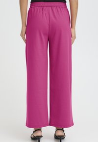 A rózsaszín bőszárú nadrág elasztikus derékpánttal és sima anyagból készült. A dizájn egyenes szabású és finom varrási részleteket tartalmaz.