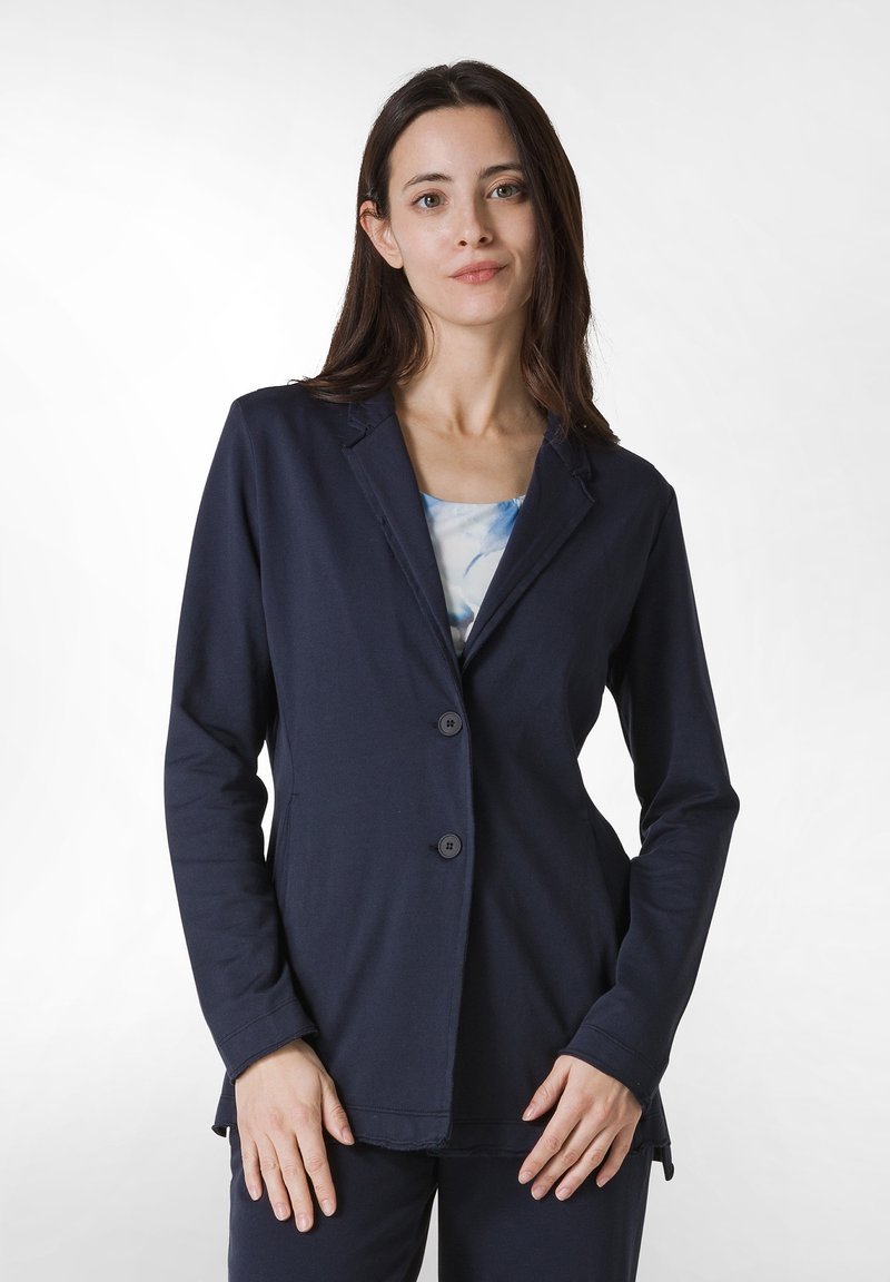 Marinblå kavaj med lång ärm i mjukt tyg; två knappar fram, subtila sömnadsdetaljer, strukturerad krage och avslappnad passform.
