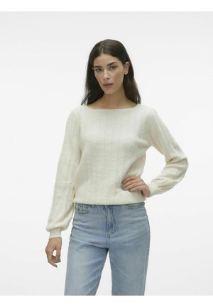 Pull en tricot de couleur crème avec un décolleté carré, texture côtelée, manches longues et rayures verticales discrètes. Porté avec un jean bleu clair.