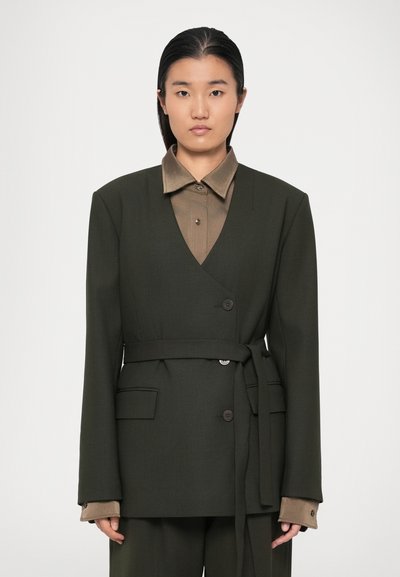 Blazer ajusté vert olive avec un décolleté en V et une fermeture à boutons. Doté d'une ceinture à la taille, de poches latérales et d'un col de chemise intérieur marron contrastant.
