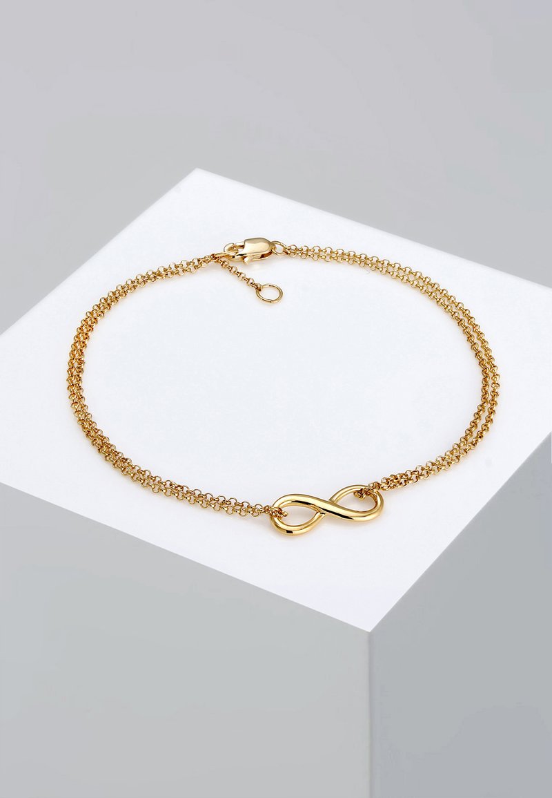 Bracelet en chaîne dorée avec un pendentif en symbole de l'infini, présentant un design de maillons texturés et un fermoir en homard pour un maintien sécurisé.