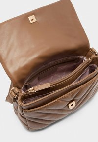 Braune Handtasche aus Kunstleder mit einem gesteppten Äußeren, goldenen Beschlägen und einem Innenfach mit Reißverschluss, ausgestattet mit einer weichen Innenauskleidung und ausreichend Stauraum.