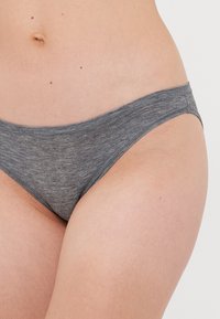Close-up of a person wearing gray cotton hipster-style underwear, showing the lower torso and upper thighs against a plain background.