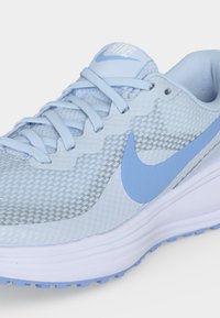 Φωτεινό μπλε παπούτσι τρεξίματος Nike με άνω μέρος από διχτυωτό ύφασμα, σχέδιο με κορδόνια και μπλε λογότυπο Swoosh σε λευκή μαλακή σόλα.