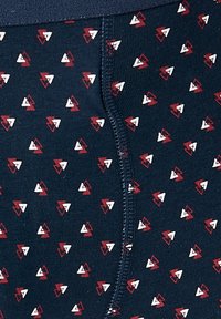 Boxer corto blu navy con un motivo geometrico di triangoli rossi e bianchi. Realizzati in tessuto a coste con una cintura comoda.