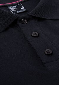 Zwarte poloshirt gemaakt van textiel met een structuur, met een kraag, drie zwarte kunststof knopen en een contrasterende roze accent bij de hals.
