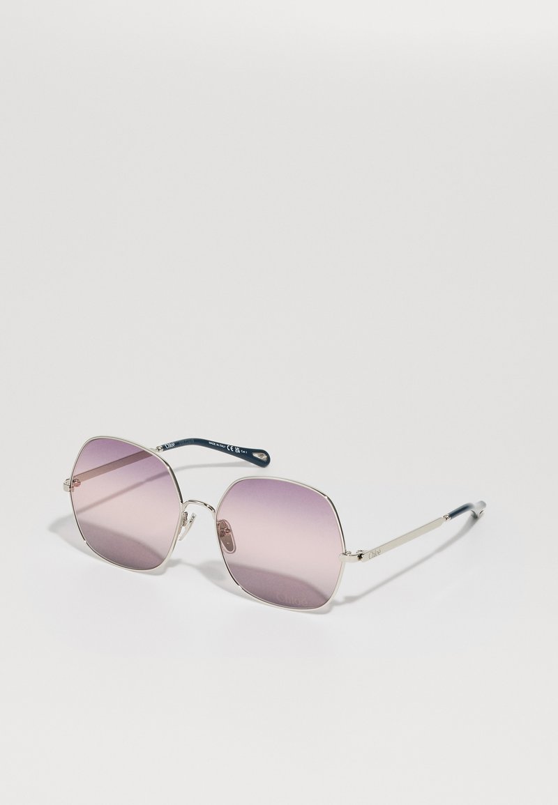 Ochelari de soare pătrați cu lentile violet degrade, ramă subțire din metal argintiu și accente de temple de culoare bleu marin. Remarcabili pentru designul lor curat și aspectul ușor.