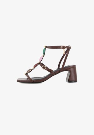 Sandalia de piel marrón con tacón, con piedras ovaladas multicolores y tachuelas doradas en las tiras, con dos pequeñas hebillas doradas y tacón de bloque.