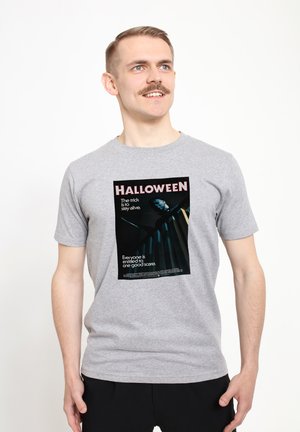 Grå bomulds T-shirt med et sort grafisk print, der har teksten "HALLOWEEN" og et billede af en karakter, der holder en kniv. Korte ærmer.