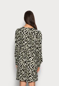 Black and cream dress with an abstract zigzag pattern; features long puff sleeves and an elasticized waist. The fabric has a smooth texture.