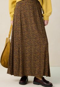 Bruin luipaardprint maxi-rok met een vloeiend ontwerp, gemaakt van zachte stof; gecombineerd met donkere schoenen en een tan schoudertas.