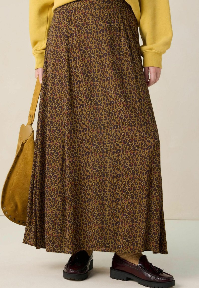 Bruin luipaardprint maxi-rok met een vloeiend ontwerp, gemaakt van zachte stof; gecombineerd met donkere schoenen en een tan schoudertas.