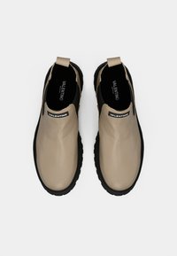 Beez slip-on kingad läikiva viimistlusega, mustade kummitaldadega ja musta aksendi ning logoga kantpalgel.