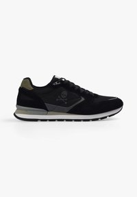 Zapatilla deportiva negra con material de malla y ante, gráfico de calavera prominente, acentos grises y suela de goma blanca. Punta redondeada y cierre de cordones.