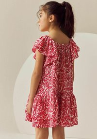 Röd och vit mönstrad klänning med korta volangärmar, en figursydd bodice och en utsvängd kjol, med en knappstängning bak.