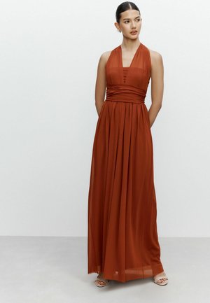 Maxi dress in rust orange, featuring a halter neckline, fitted bodice, and flowing skirt. Made from lightweight, textured fabric.