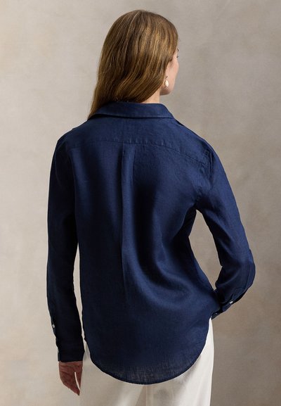 Marineblå lin-skjorte med avslappet passform, lange ermer, klassisk krage og knappet mansjett. Har buet kant og teksturert stoff.