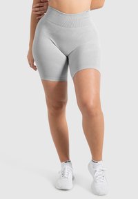 Grijze high-waisted shorts van een gladde, rekbare stof met subtiele diagonale strepen; gedragen met witte sportschoenen.