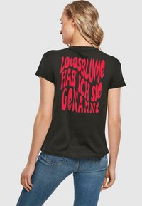 Sort t-shirt med korte ærmer, prydet med stort, fedt rødt tekst på ryggen, der står "Lotosblume hab' ich sie genannt."