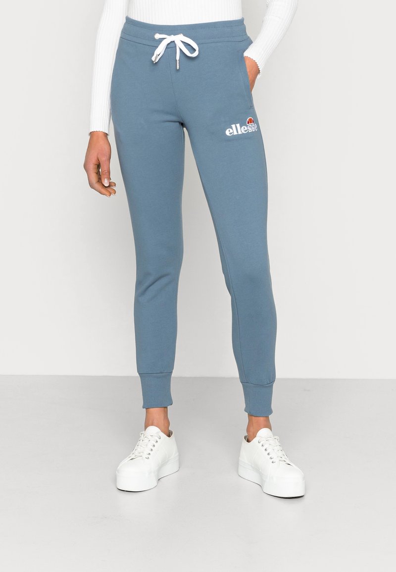 Light blue sweatpants made of cotton blend, with a drawstring waist and tapered legs, featuring a small white logo on the thigh.