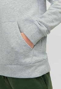 Felpa grigia con una texture morbida, dotata di tasca a marsupio e polsini a coste. L'orlo è leggermente elastico per una vestibilità sicura.