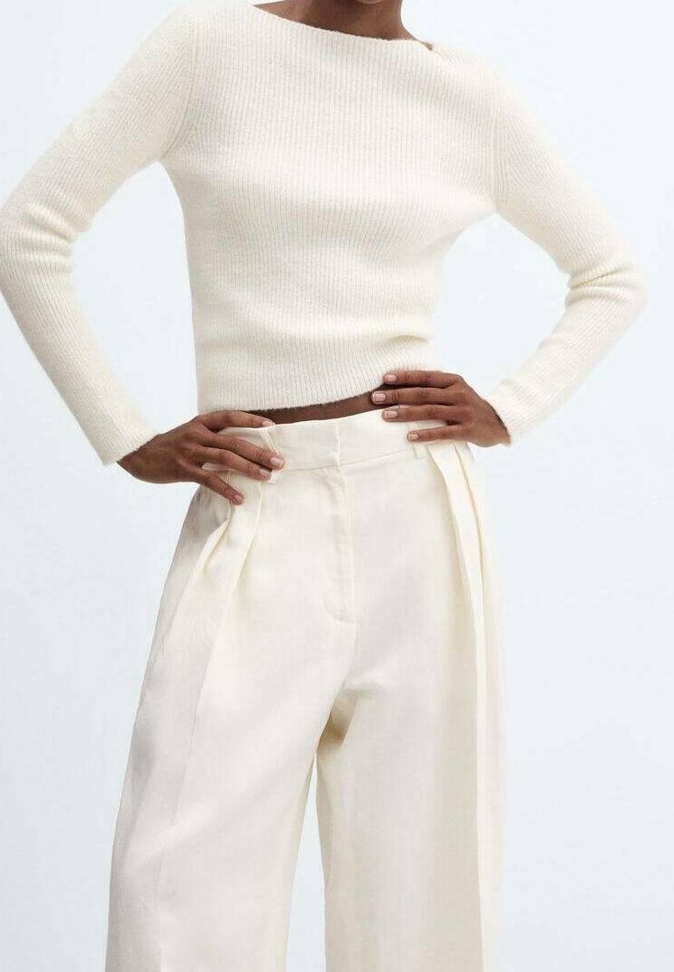 Pull en maille côtelée, couleur crème, avec un décolleté bateau, associé à un pantalon taille haute à jambes larges en tissu doux, couleur blanc cassé.