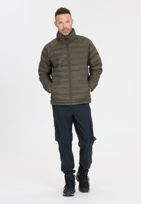 Oliven grøn isoleret jakke med høj krave, lynlås lukning og vandret quiltet overflade, parret med marineblå cargo bukser og sorte støvler.