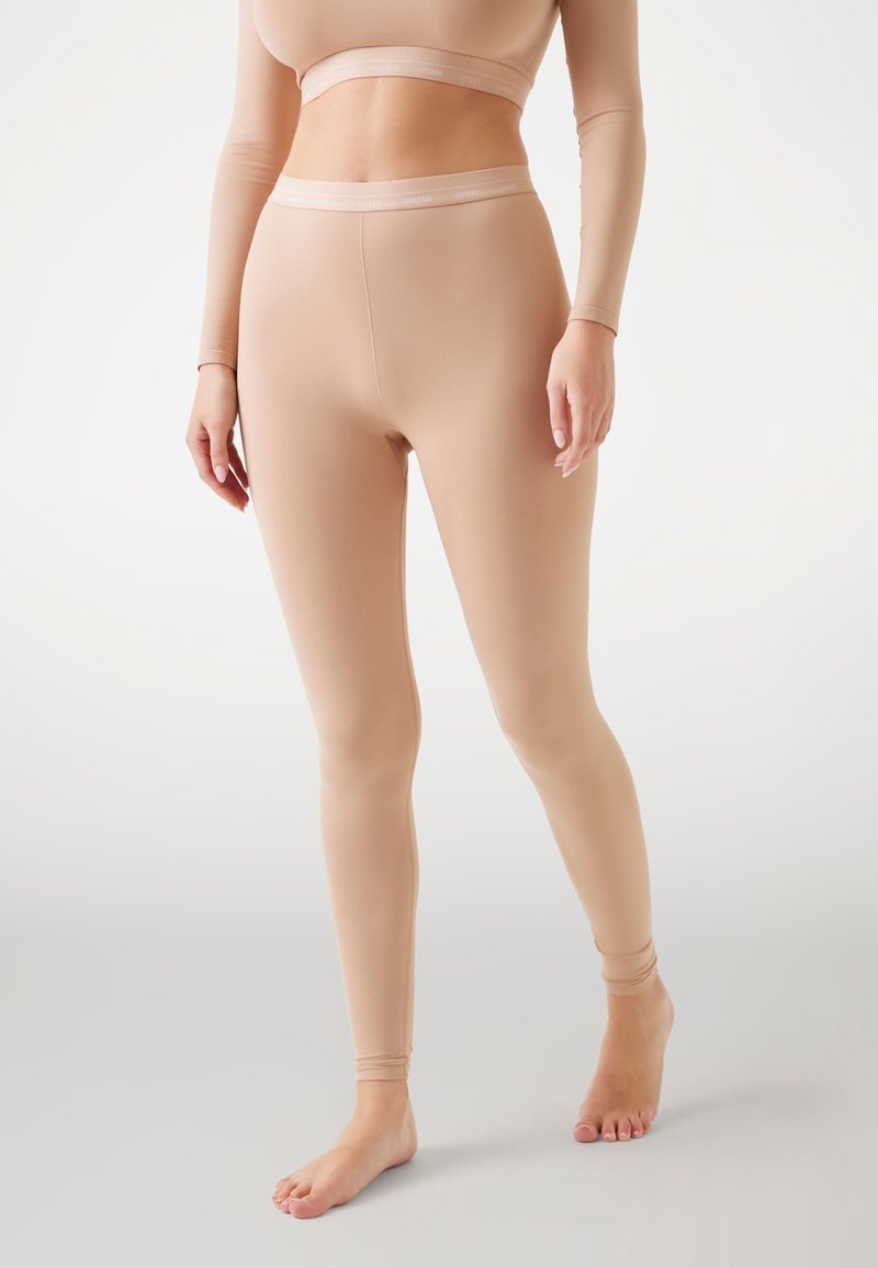 Nude leggings tillverkade av ett stretchigt material, med en sömlös design, en åtsittande silhuett och ett elastiskt midjeband.