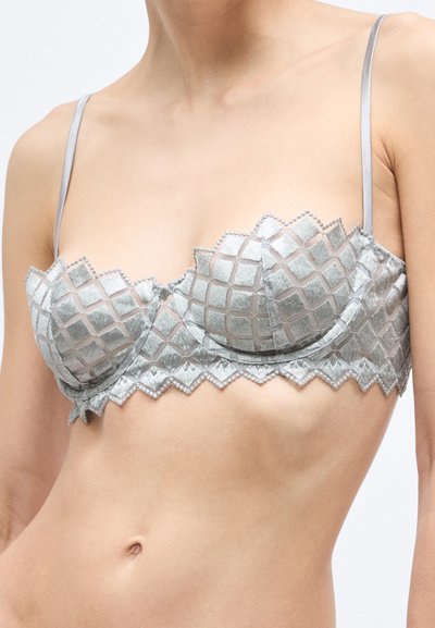Sivá čipkovaná braletka s vzorom, s vlnitým lemom a nastaviteľnými saténovými ramienkami. Má textúrovanú mriežku a zapínanie na háčik.