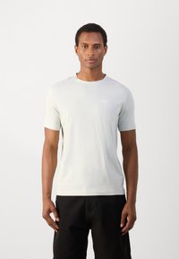Lichtgrijs T-shirt met korte mouwen en een ronde hals, gladde textuur en een klein logo op de borst, gecombineerd met zwarte shorts.
