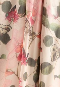 Tissu translucide présentant un motif floral avec des fleurs roses, des feuilles vertes et des papillons, créant une apparence en couches et texturée.