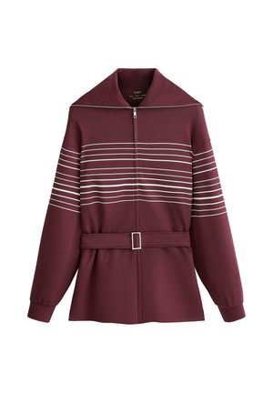 Bordó színű cipzáras dzseki széles gallérral, vízszintes fehér csíkokkal a mellkason és a felső karokon, valamint hozzáillő anyagból készült öv csattal.