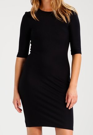 Musta, vartalonmyötäinen mekko, jossa on lyhyet hihat ja pyöreä pääntie. Valmistettu sileästä, venyvästä kankaasta, se kapenee polveen saakka.